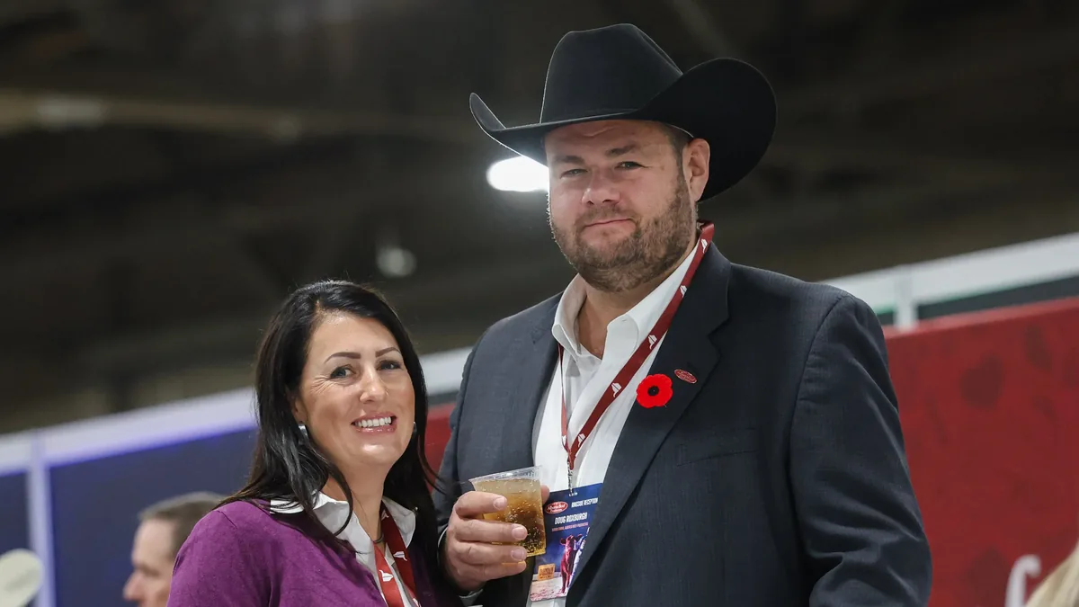 Couple in western wear enjoying drinks at a ringside reception during a cattle show